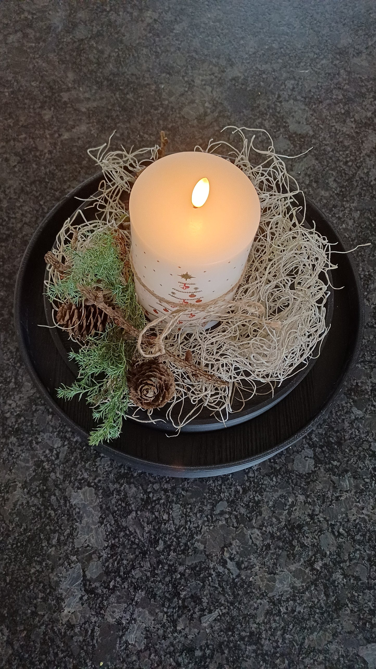 Sort rund 3 D printet ramme, hvori der er lagt en træplade med melaminoverflade, der er afskær fra dansk køkkenproducent. 28 cm i diameter.