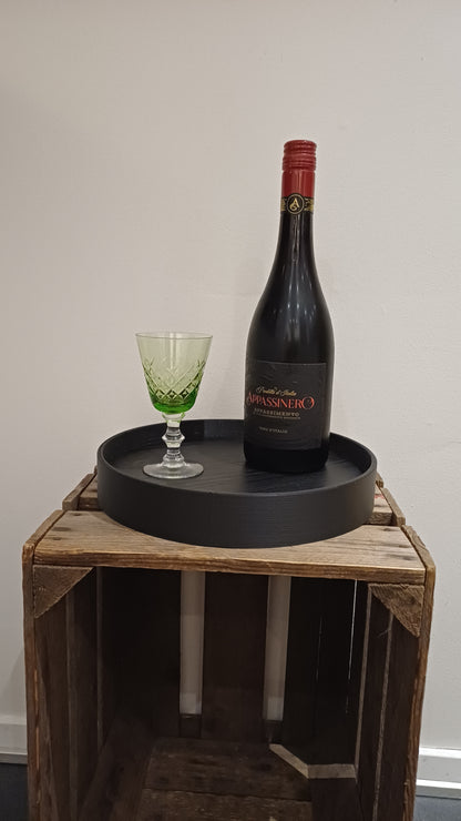 Sort rund 3 D printet ramme, hvori der er lagt en træplade med melaminoverflade, der er afskær fra dansk køkkenproducent. 25 cm i diameter.